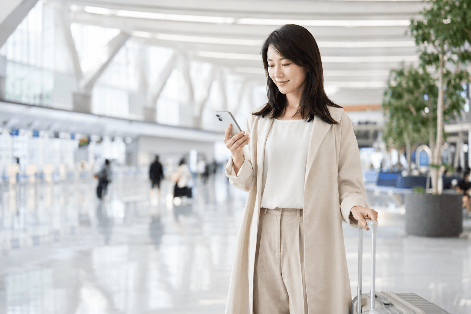 空港でスマートフォンを確認する旅行者
